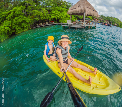 Mother and son tourists kayaking together on the crystal-clear turquoise waters of Lake Bacalar, Mexico. Family bonding, outdoor adventure, and tropical travel concept in a serene natural setting