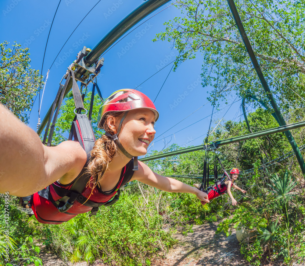 Woman in helmet flying on a zipline over a lush tropical park. Thrilling adventure surrounded by nature, perfect for eco-tourism and adrenaline seekers. Extreme sports and outdoor exploration concept
