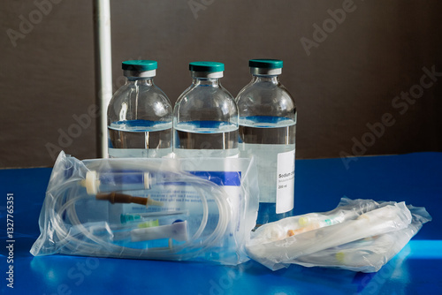 Saline solution for injections in a glass bottle, IV drip with saline solution in sunlight – an image of hope and recovery.