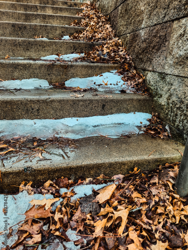 close-up snow melting on rustic weathered concrete stairsteps covered in leaves in early spring. gray brick wall installed to the side. going up the stairs healthy lifestyles abstract background. close-up snow melting on rustic weathered concrete stairsteps covered in leaves in early spring. gray brick wall installed to the side. going up the stairs healthy lifestyles abstract background.