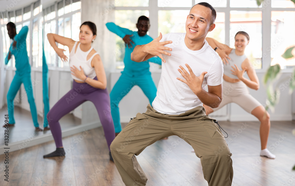 Fototapeta premium Young guy and international dancers preparing their modern dance performance at light dance studio