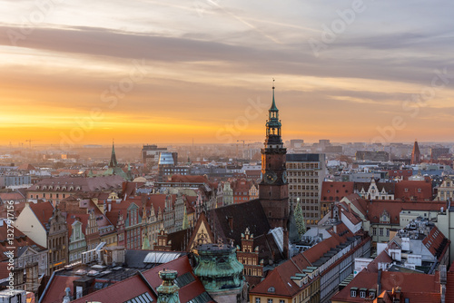 Aerial view of Wroclaw, Poland, at sunset, showcasing stunning blend of medieval and modern architecture with red rooftops, historic churches, and contemporary buildings glowing in golden light.