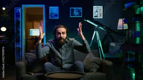 Annoyed supporter watching sports broadcast, howling at awful team mistake, throwing pillow at TV. Angry man watching soccer match fuming, screaming, irritated by chance missed by player, camera B