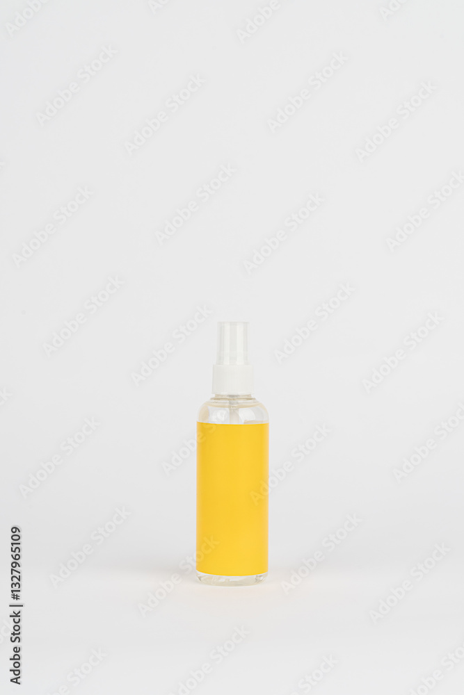Minimalist Transparent Spray Bottle with Yellow Label on White Background Minimalist Transparent Spray Bottle with Yellow Label on White Background