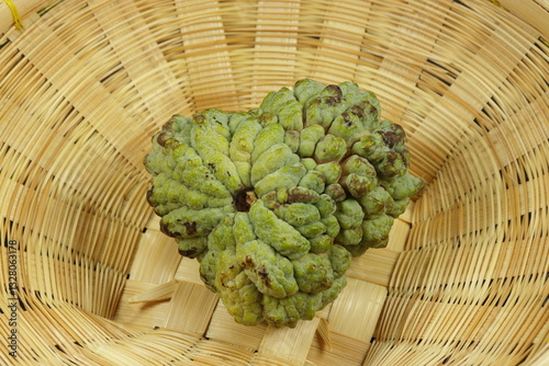 Fresh and organic custard apple on the wooden basket. Famous tropical fruit in Asia. 