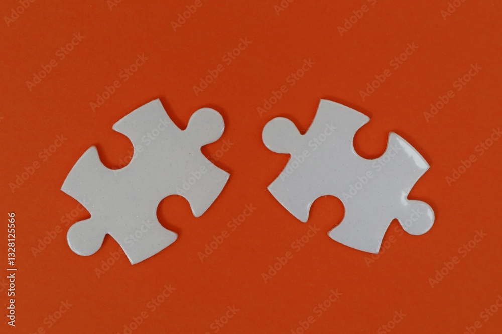 Obraz premium Two white puzzles on an orange background