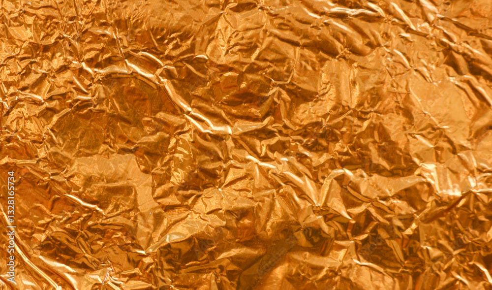 Crumpled gold foil as background with light and shadow texture details. Shiny gold foil wallpaper. Crumpled gold foil as background with light and shadow texture details. Shiny gold foil wallpaper.