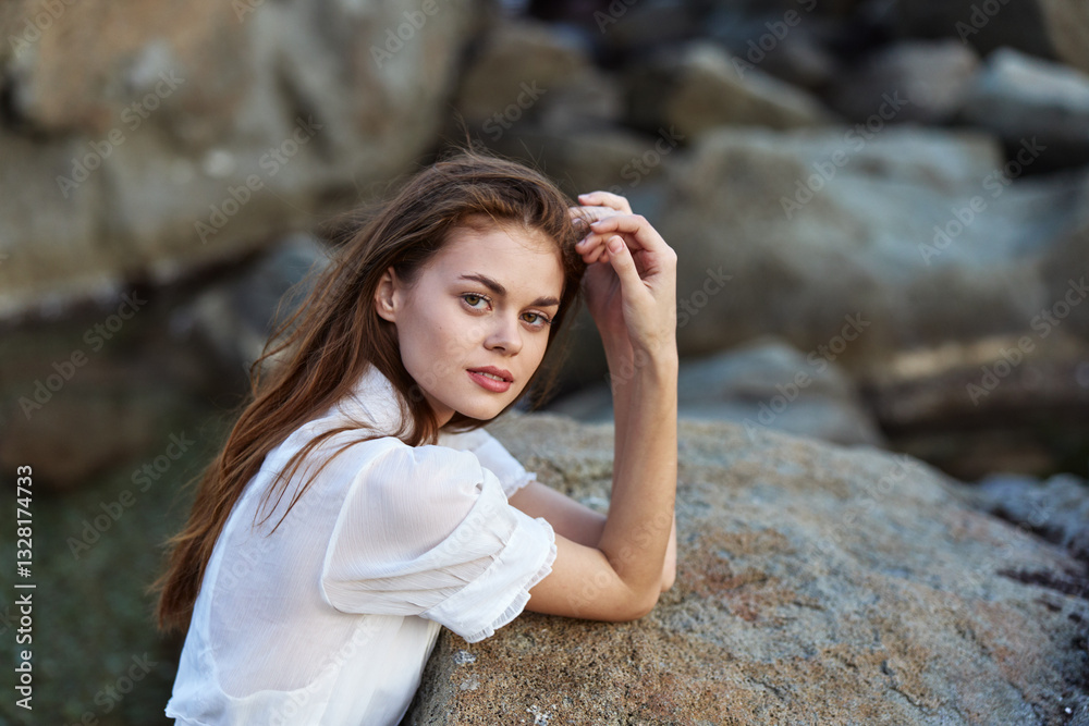 Serene young woman enjoying the ocean view while sitting on a rock Serene young woman enjoying the ocean view while sitting on a rock