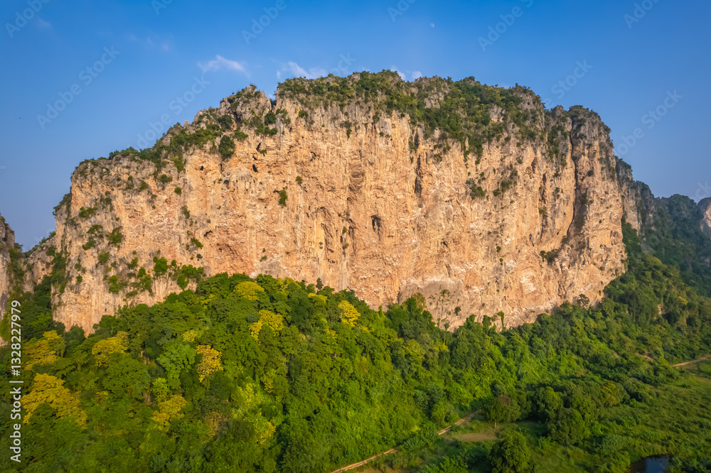 This rocky mountain is called Khao E-Bid, located in Phetchaburi Province, Thailand. It appears orange as it is illuminated by the setting sun. This rocky mountain is called Khao E-Bid, located in Phetchaburi Province, Thailand. It appears orange as it is illuminated by the setting sun.
