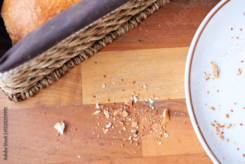 Obraz na plátně Crumbs scattered on wooden table beside a bread basket