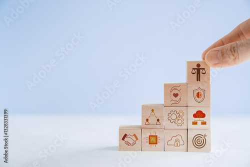 Hand holding wooden block with Ethical icons, business ethics and corporate compliance concept
