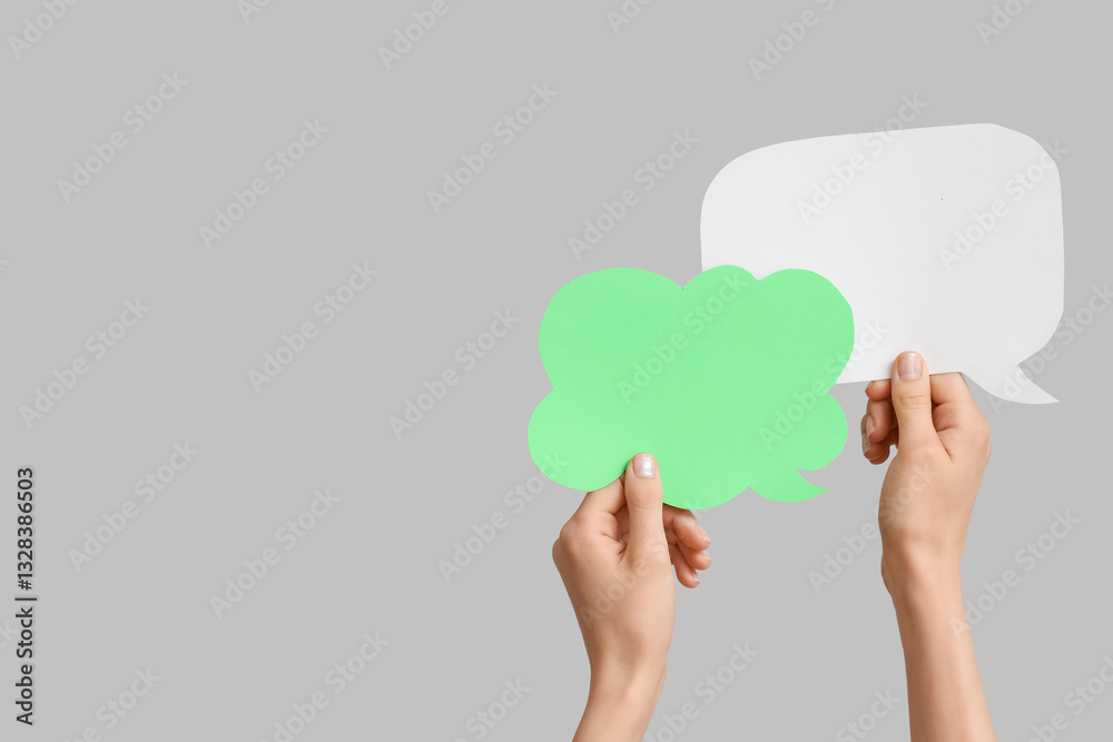Female hands with speech bubbles on grey background Female hands with speech bubbles on grey background