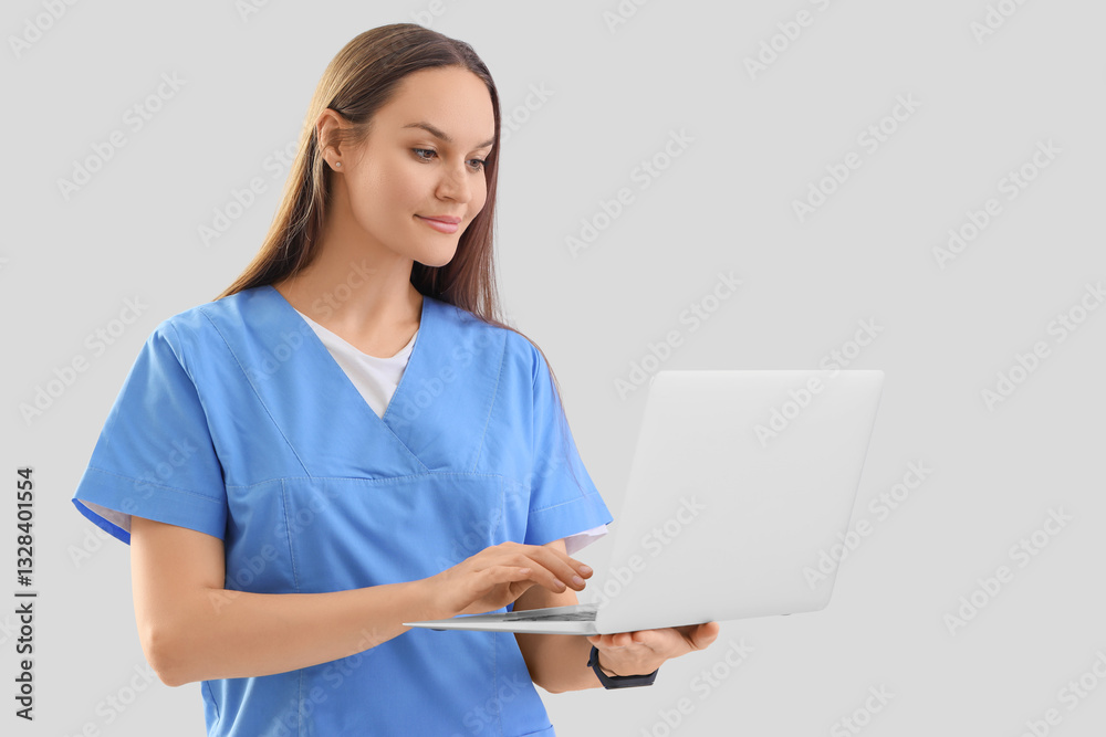 Female medical intern using laptop on light background Female medical intern using laptop on light background