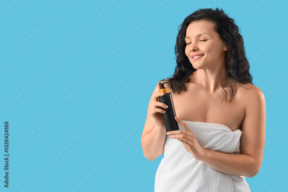 Young woman in towel after shower with cosmetic bottle on blue background Young woman in towel after shower with cosmetic bottle on blue background