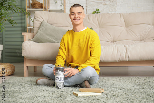 Male student putting money in jar bank in room. Concept of savings for education