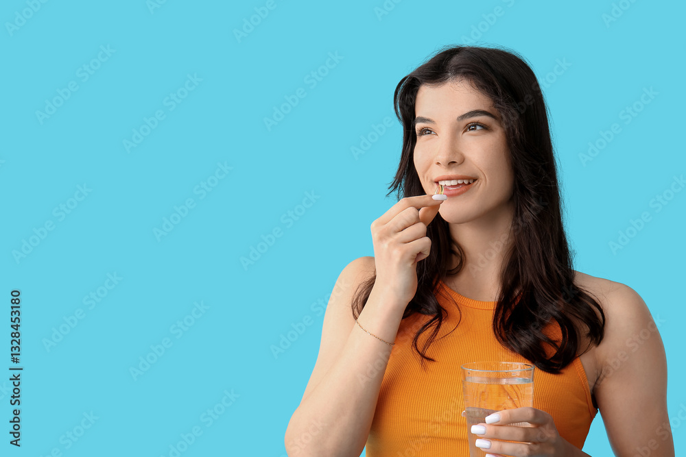 Beautiful young happy woman with glass of water and fish oil capsule on blue background Beautiful young happy woman with glass of water and fish oil capsule on blue background