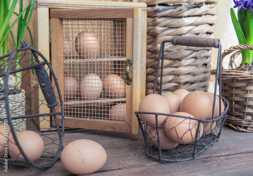 chicken eggs in a decorative box and metal baskets on a table in front of a w...