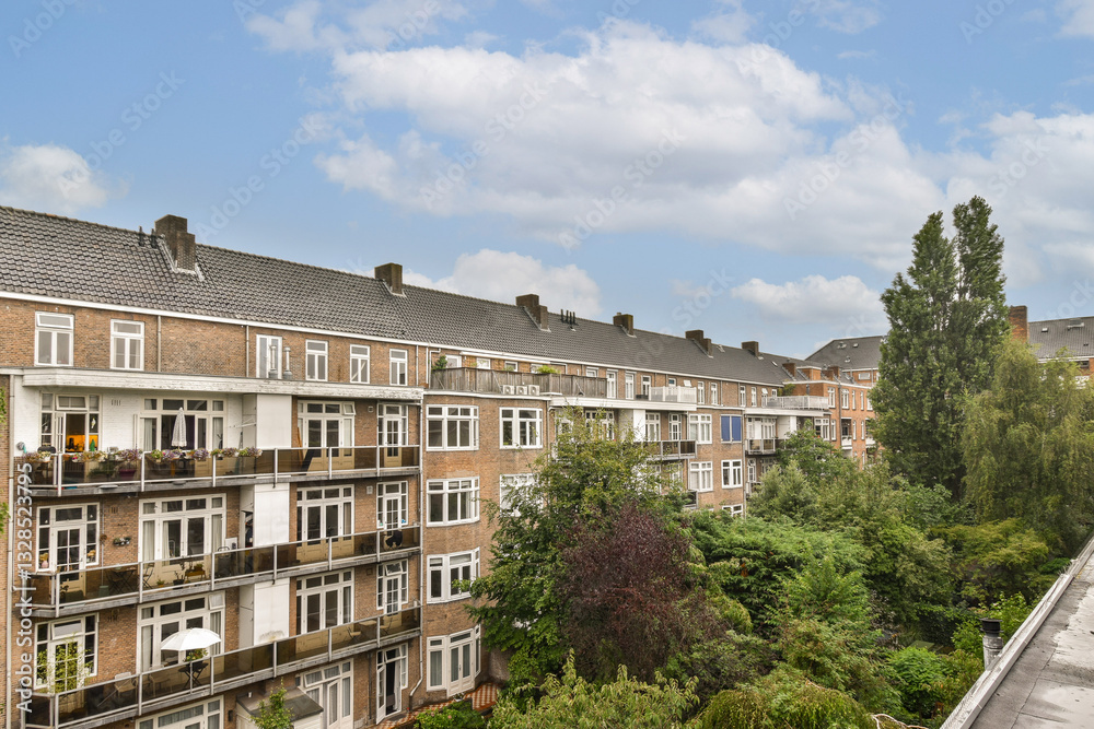 Fototapeta premium A view of a residential apartment complex showcasing modern architecture set against lush greenery and colorful foliage.