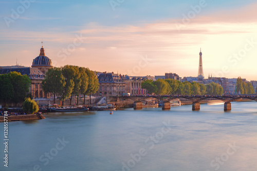 Cityscape of Paris and the Seine River at sunset, with the historic Institut de France on the left, the Pont des Arts bridge in the middle, and the iconic Eiffel Tower in the background.