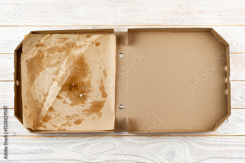 Empty pizza box with breadcrumbs on white wooden table flat lay view