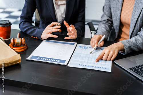 Two female lawyers in business suits meet at wooden desk, shaking hands over contract paper. wooden gavel and scales justice as discuss legal compliance, corporate law, dispute resolution.