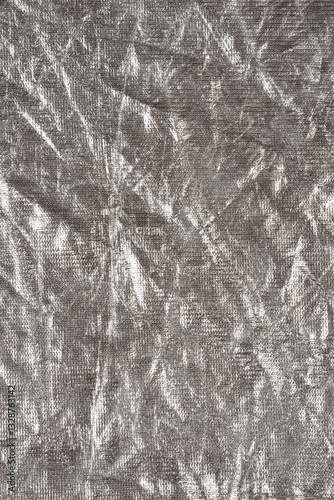 A close-up shot of crumpled silver fabric, showcasing its reflective surface and intricate texture
