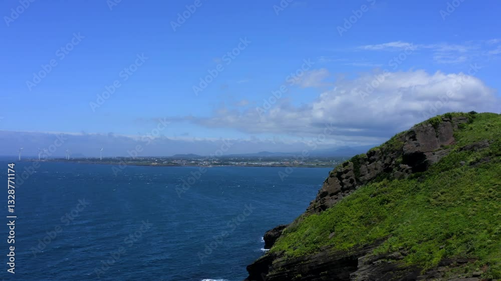 Drone gently rising while moving forward along Jeju coastal cliffs showing deep blue ocean, distant shoreline and sky. Drone gently rising while moving forward along Jeju coastal cliffs showing deep blue ocean, distant shoreline and sky.