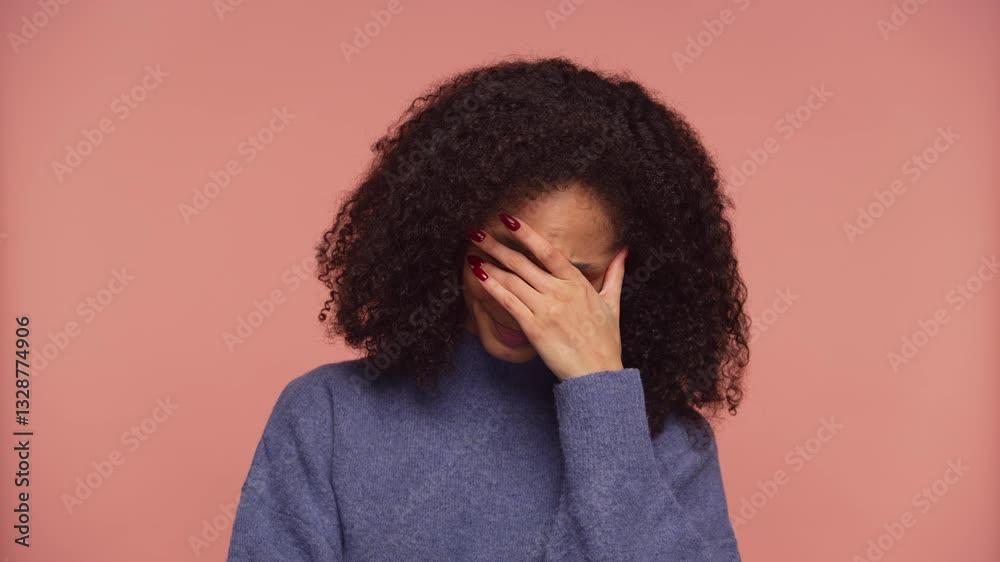 Upset woman covering face in distress on pink background
