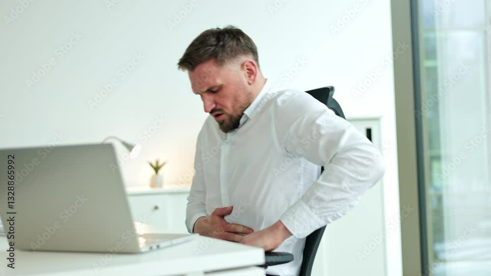 Businessman experiencing severe stomach pain while working at his desk. He's holding his stomach with a pained expression. Businessman experiencing severe stomach pain while working at his desk. He's holding his stomach with a pained expression.