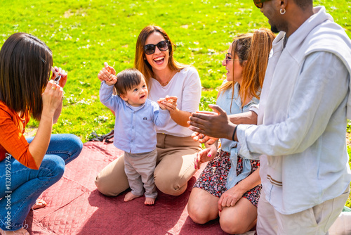 Happy multi ethnic family taking pictures and playing with baby boy in a park