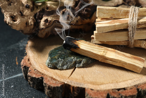 Palo Santo stick smoldering on dark table, closeup