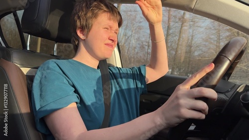 young woman with short haircut behind the wheel has problems with driving because of sun in eyes in cold season