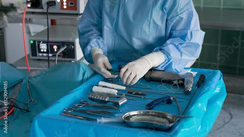 A surgeon in sterile gloves organizes surgical instruments on a tray in an operating room, ensuring precision and readiness for a medical procedure in a hospital setting