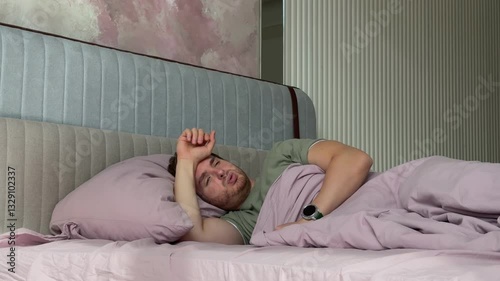 handsome young man suffers from heat in bed, summer is stuffy or feels sick