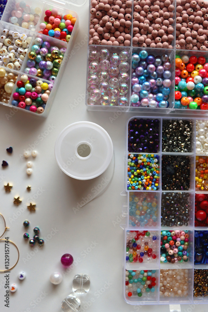Hand figurine, colorful friendship bracelets, necklaces, various beads and DIY supplies on the table. Making jewelry at home. Flat lay.
