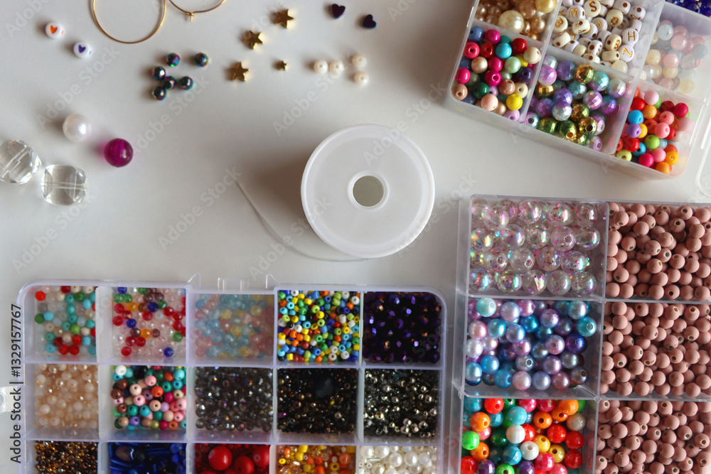 Hand figurine, colorful friendship bracelets, necklaces, various beads and DIY supplies on the table. Making jewelry at home. Flat lay.