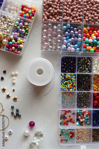 Obraz na płótnie Hand figurine, colorful friendship bracelets, necklaces, various beads and DIY supplies on the table. Making jewelry at home. Flat lay. w salonie