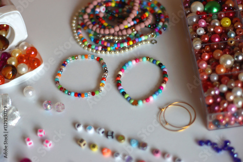 Obraz na płótnie Friendship bracelet spelled with letter beads. Colorful handmade bracelets and various jewelry making supplies. Selective focus, white background. w salonie