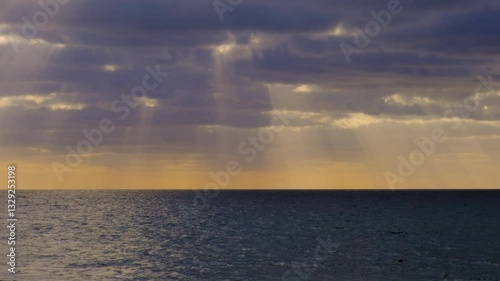 Sunrise Timelapse. Time lapse of dramatic light rays breaking through dark clouds in morning sky over ocean