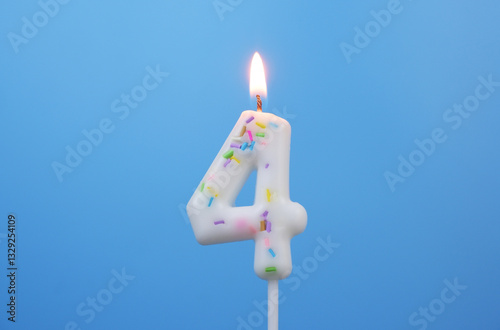 Burning white birthday candle on blue background, number 4. photo