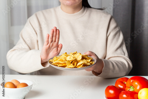 Closeup of woman making stop sign to refuse fried chips for dieting and healthy eating. Vegetable plate. Weight loss concept.