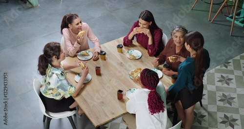 Indian young adult woman group old lady sitting around table talk gossip eat break fast food share lunch at job work place happy female girl drink juice pick up coffee cup have fun joy spend day time