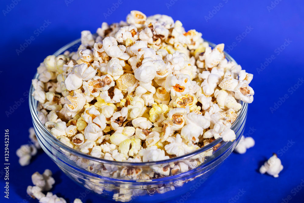 Bowl full of healthy butter popcorn on blue background Bowl full of healthy butter popcorn on blue background