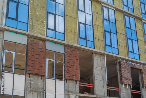 Construction work on the exterior cladding. Laying of thermal insulation material on the walls. Insulation of the house. Preparing the house for winter. The wall of a house under construction.