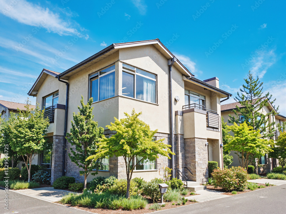 Fototapeta premium Modern suburban home with well-maintained landscaping and blue sky, exterior view from street on sunny day.