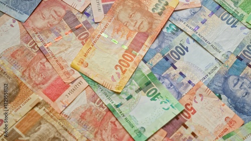 Various south african rand banknotes featuring mandela laid out in a scattered arrangement with vibrant colors, highlighting the diverse denominations of south africa's currency.