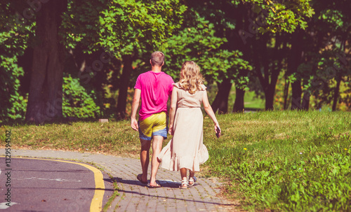 Fototapeta Naklejka Na Ścianę i Meble -  A man and a woman walk in a summer park
