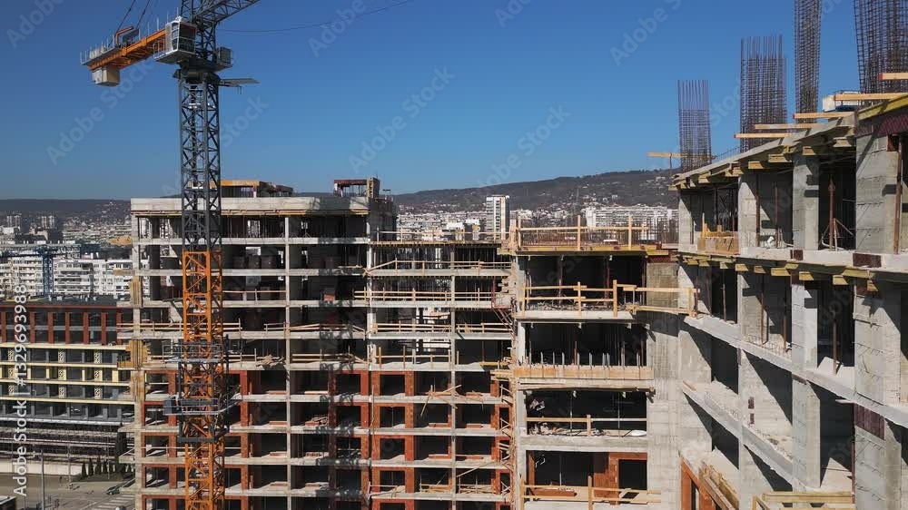 Construction site of a high-rise building at sunny day. The structure's concrete framework, cranes, and scaffolding are bathed in bright sunlight, highlighting urban development Construction site of a high-rise building at sunny day. The structure's concrete framework, cranes, and scaffolding are bathed in bright sunlight, highlighting urban development