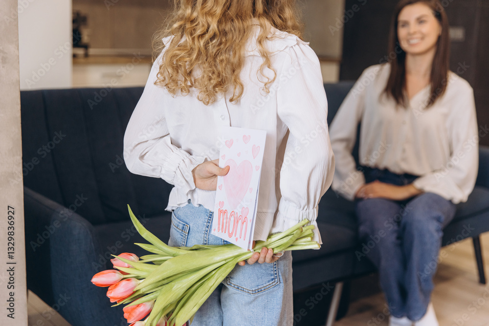 Obraz premium Daughter surprising her mother with greeting card and tulips for Mother's Day