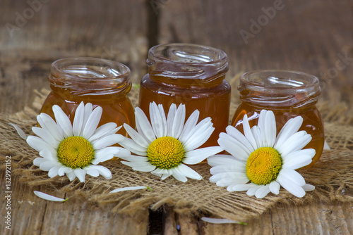 honey an daisy flowers on wooden background